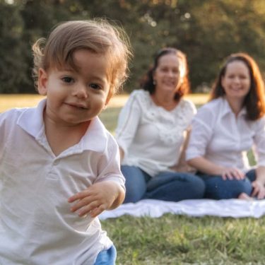 A joyful family enjoying a picnic in the park with a playful toddler in the foreground.
